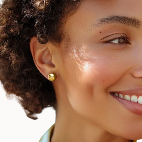 Close-up of a woman wearing a gold earring with a blurred background