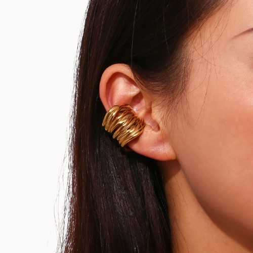 Gold earring worn by a person with dark hair on a white background