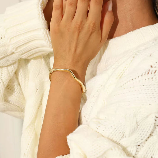 Gold bracelet on a wrist with a white textured fabric background