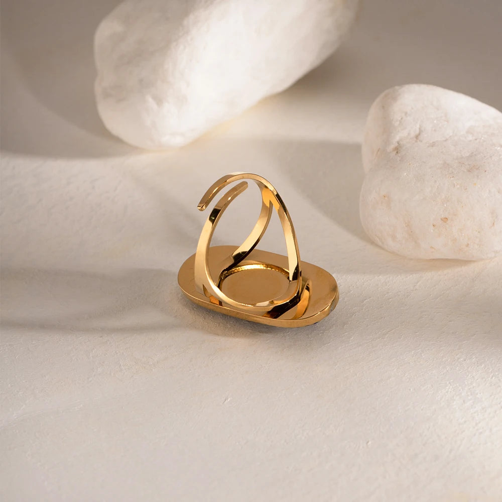 Gold ring on a textured beige surface with light-colored stones in the background