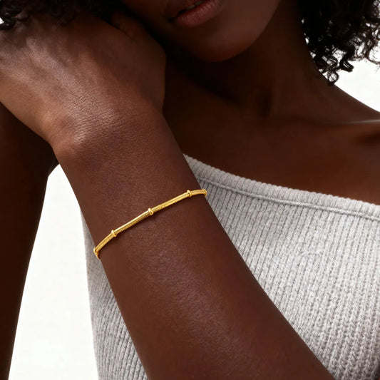 Gold bracelet on a person's wrist with a neutral background