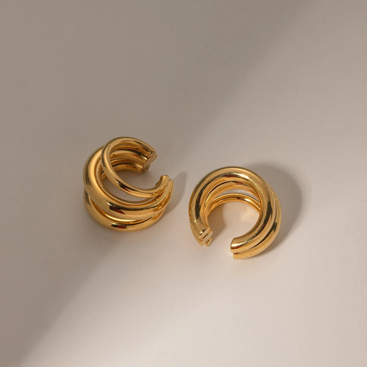 Pair of gold hoop earrings on a beige background