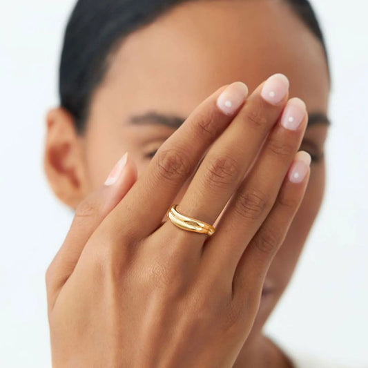 Close-up of a hand with a gold ring on a blurred background