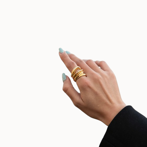 Hand wearing multiple gold rings on a white background