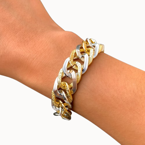 Gold and silver chain bracelet on a wrist against a white background