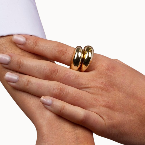 Close-up of a hand wearing two gold rings on a white background