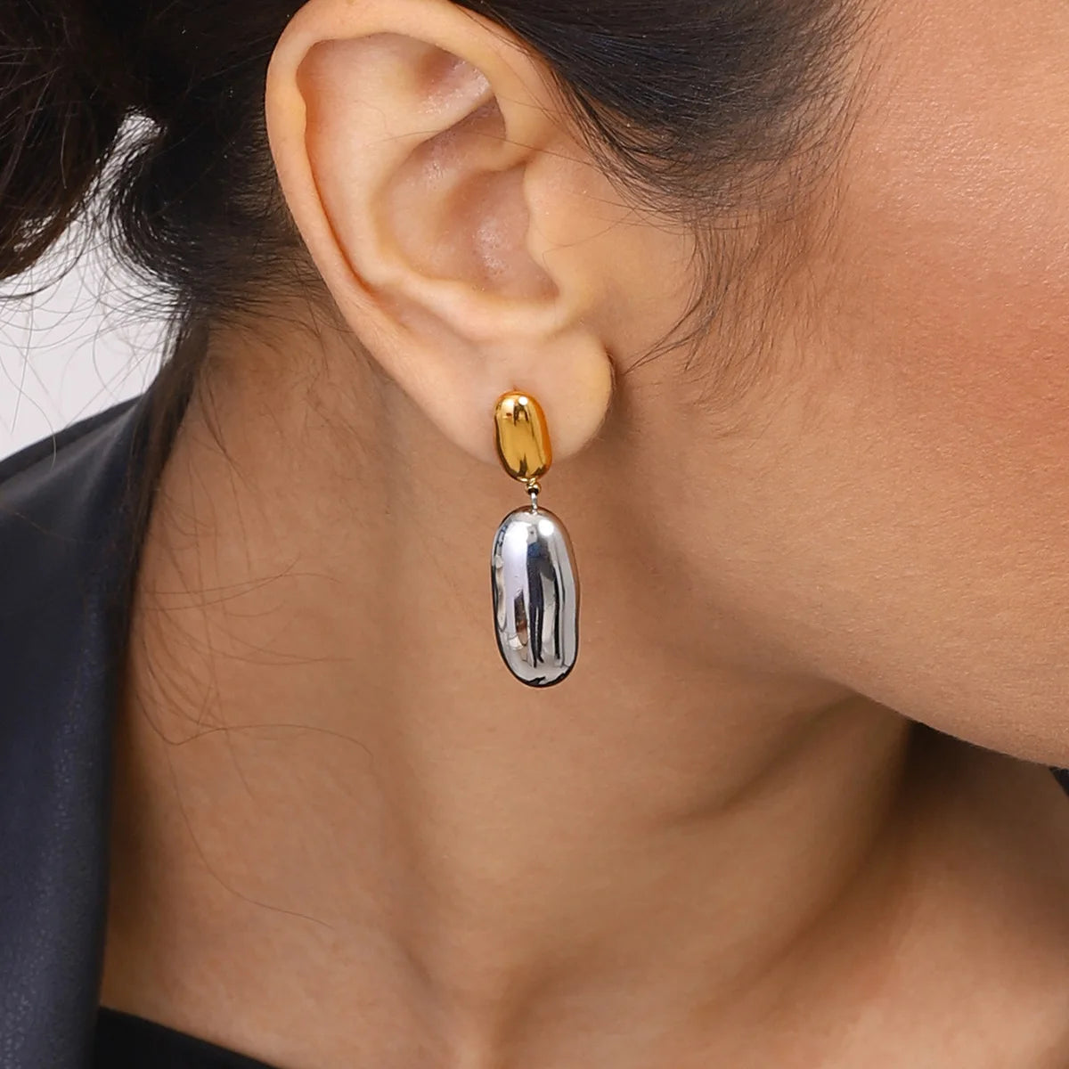 Close-up of an ear wearing a gold and silver dangling earring.