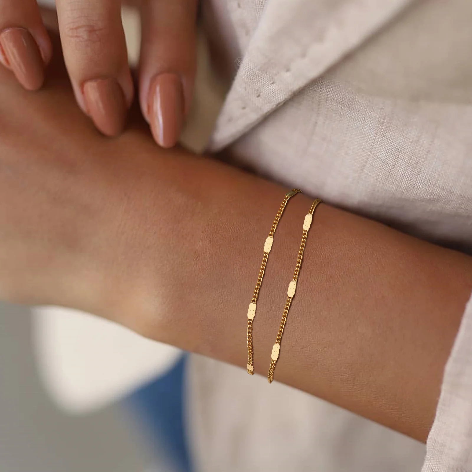 Gold bracelet on a wrist with a neutral background
