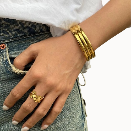 Hand wearing a gold ring and bracelet on a white background