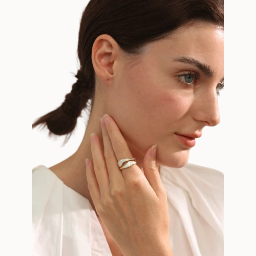 Woman wearing a gold ring on her finger with a plain background
