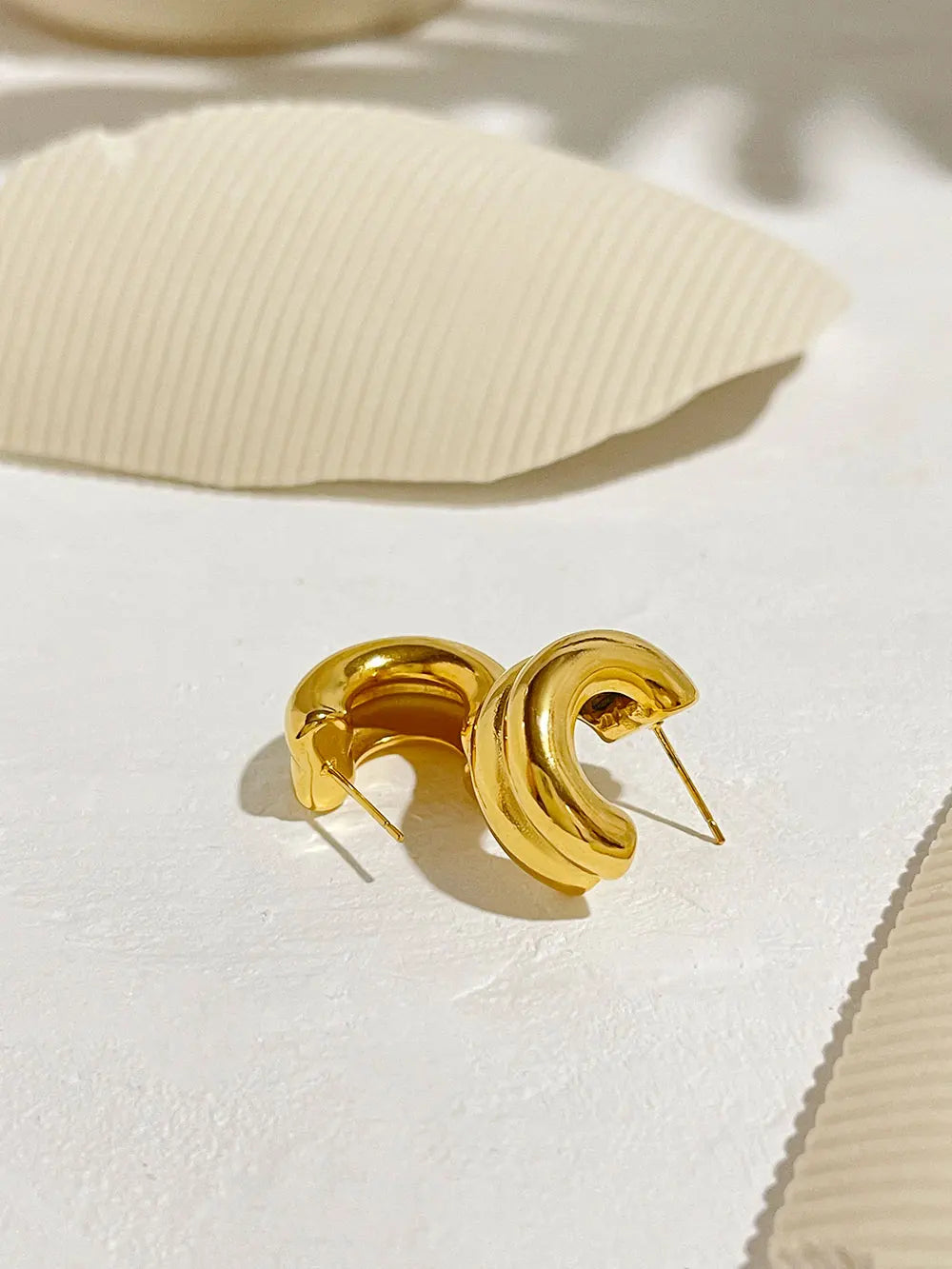 Gold hoop earrings on a textured beige surface