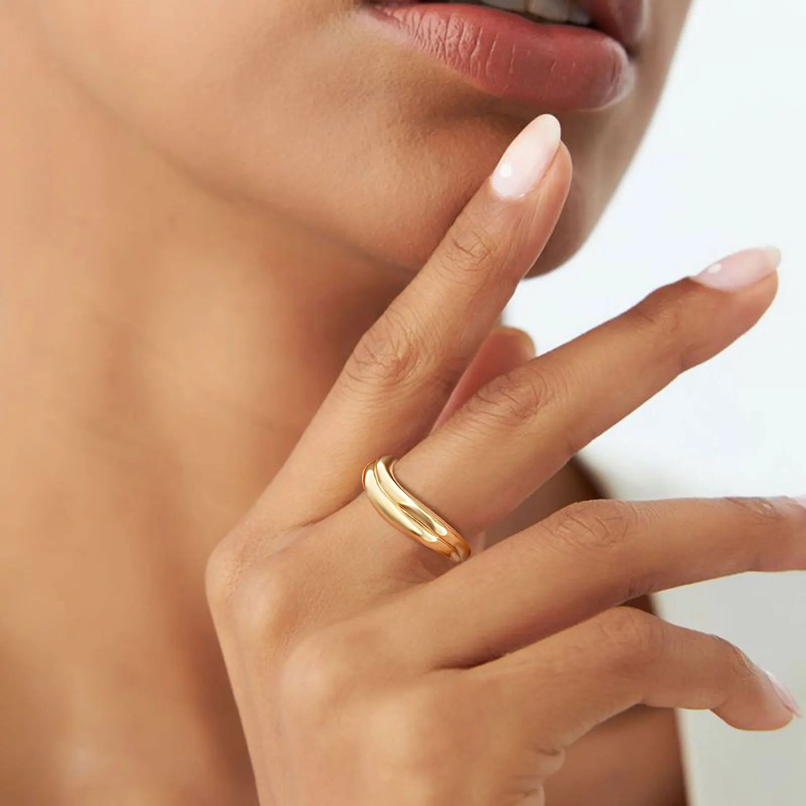 Close-up of a hand wearing a gold ring with a blurred background
