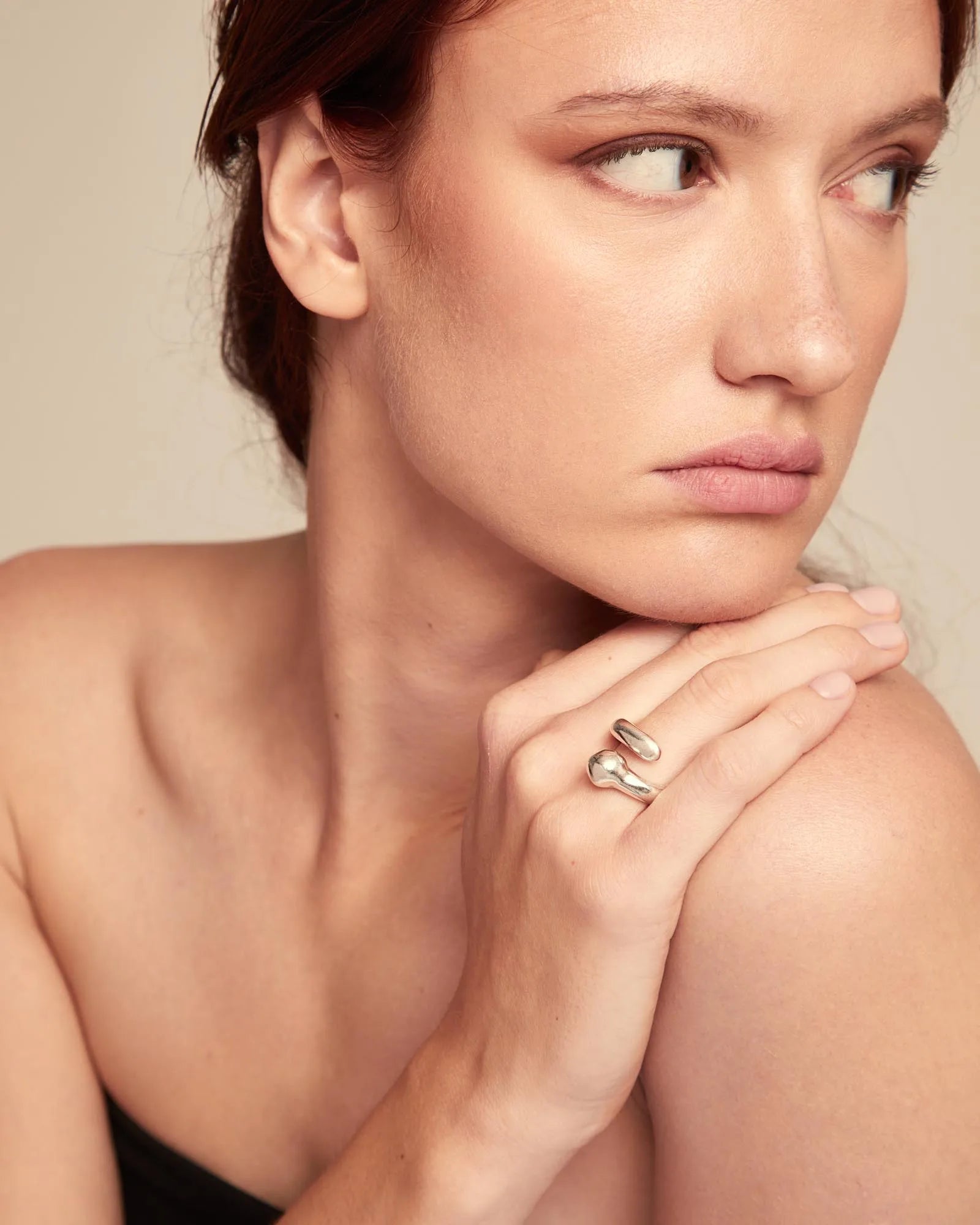 Woman wearing a silver ring on her hand with a neutral background