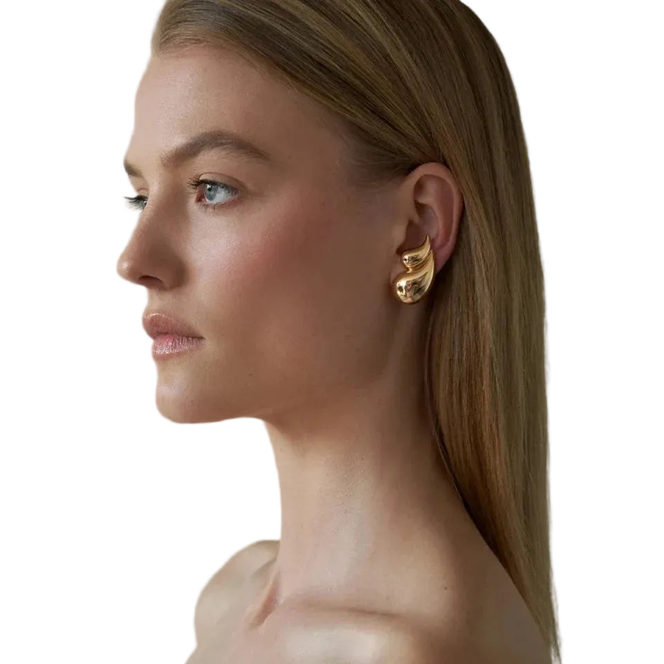 Woman wearing gold earrings against a neutral background