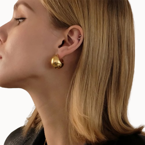 Close-up of a woman wearing gold heart-shaped earrings on a white background