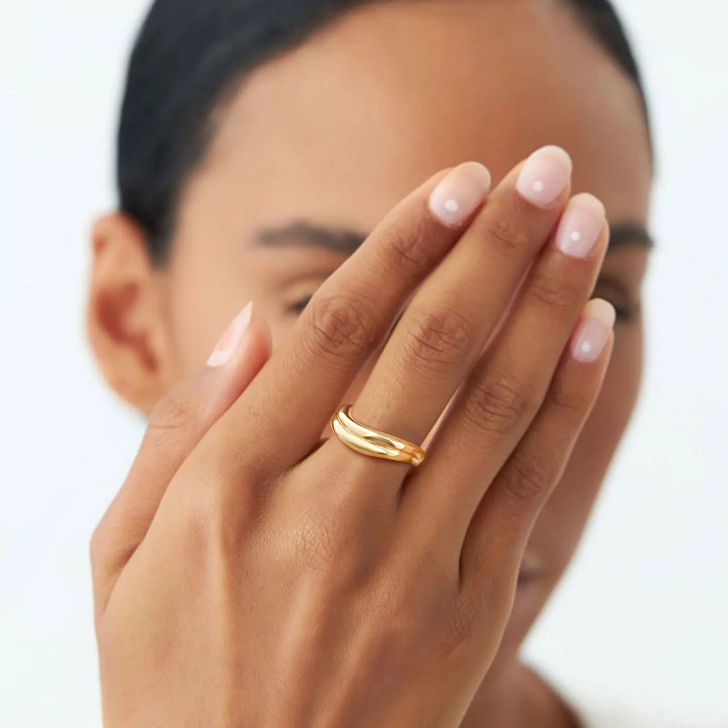 Close-up of a hand with a gold ring on a blurred background