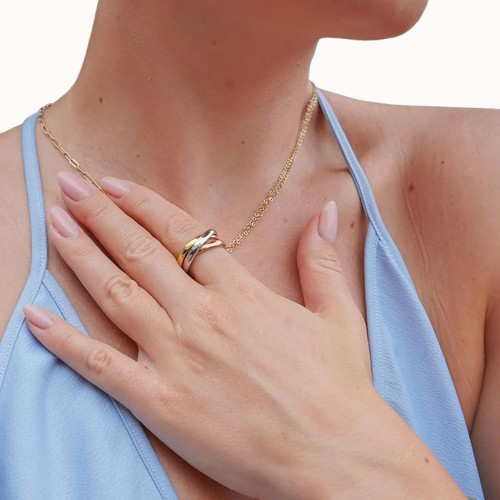 Woman wearing a gold necklace and ring on a white background