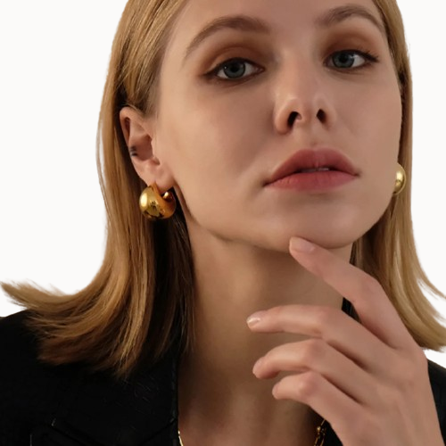 Close-up of a woman wearing gold earrings with a neutral background