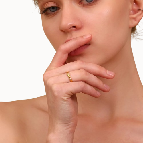 Woman with a gold ring on her finger, touching her lips against a white background