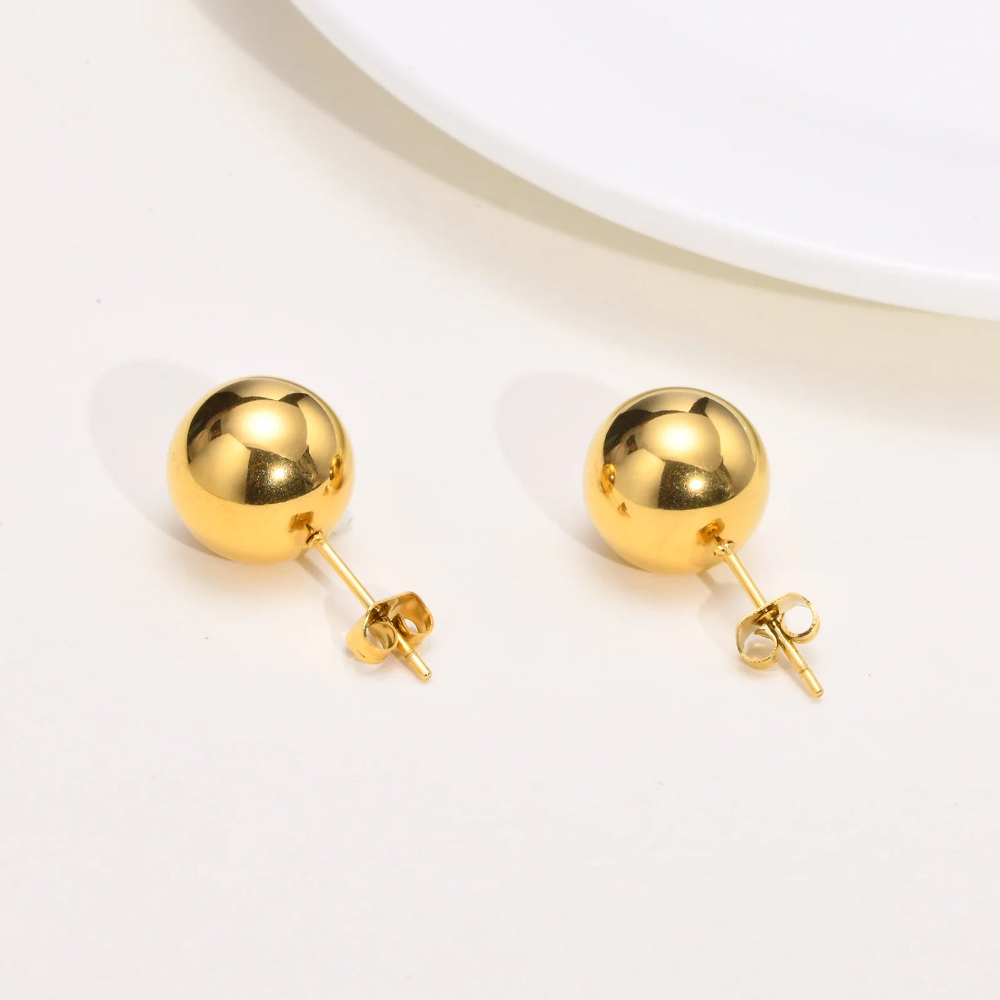 Pair of gold spherical earrings on a light beige background
