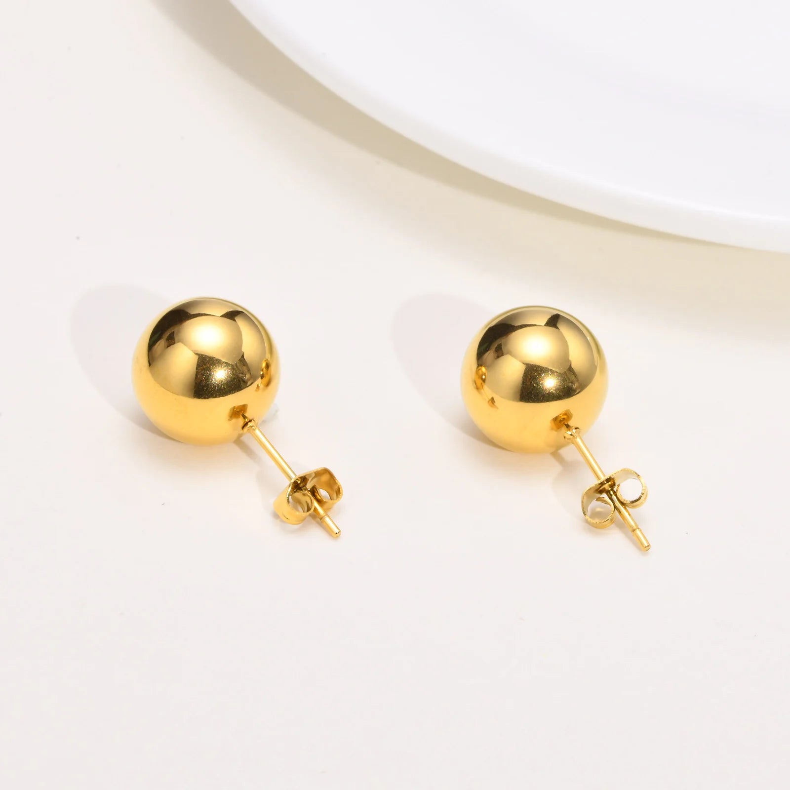 Pair of gold spherical earrings on a light beige background