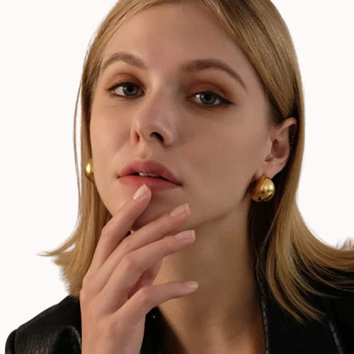Close-up of a woman wearing gold earrings with a neutral background