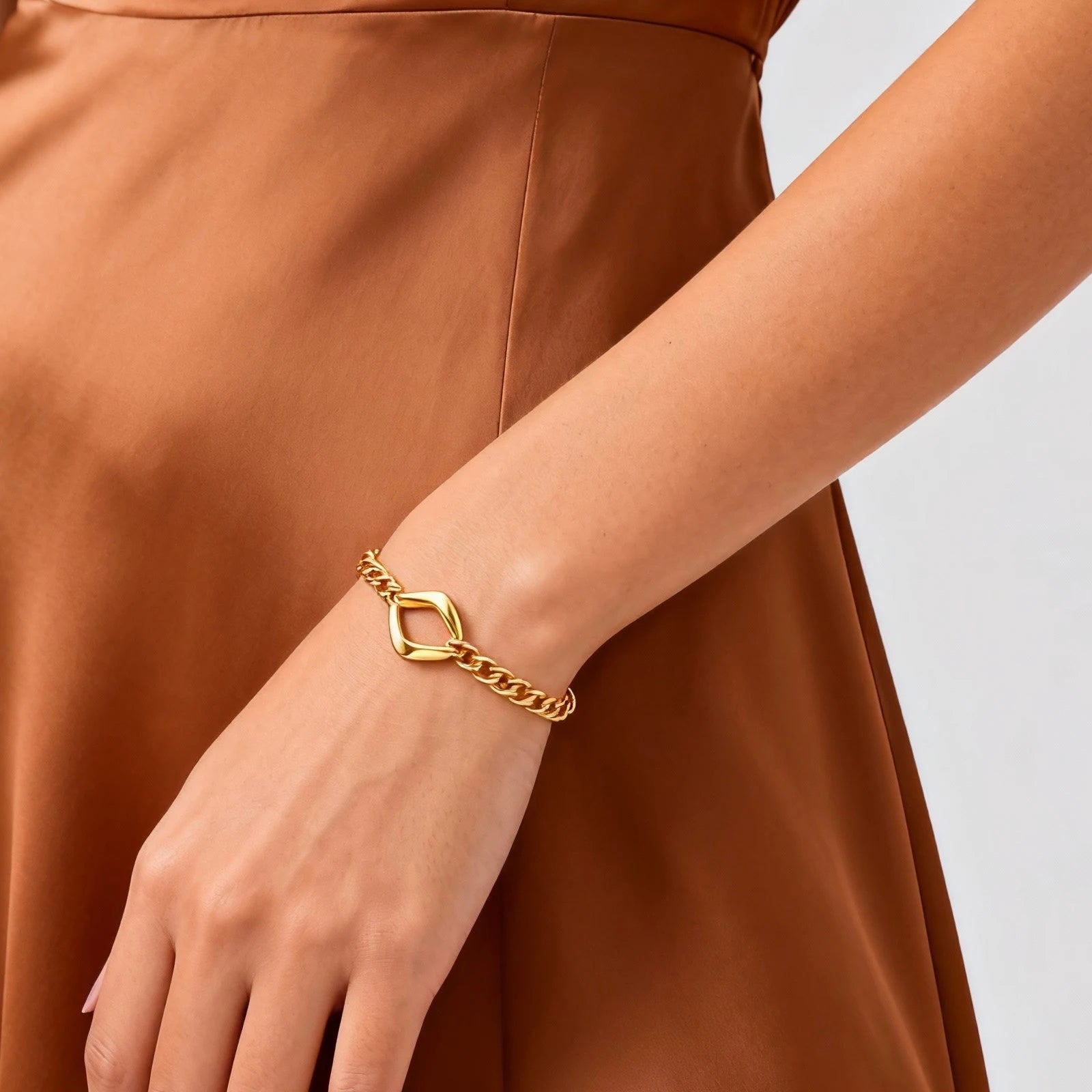 Gold bracelet on a wrist with a brown dress