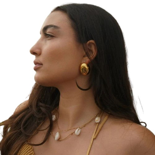 Woman wearing gold jewelry with a plain background